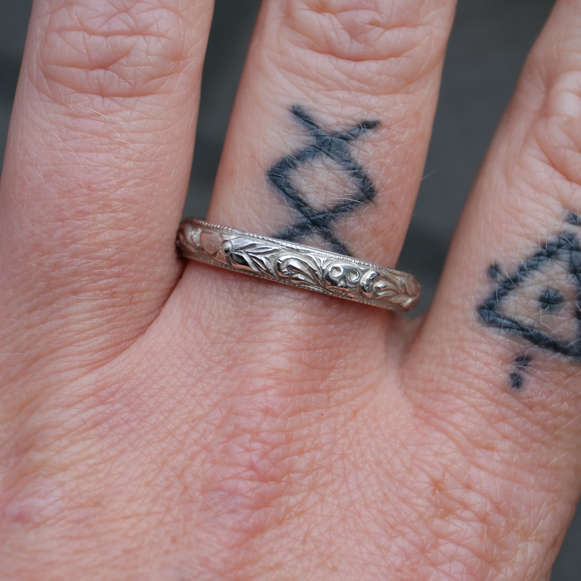 Silver band engraved with skulls, flourishes and flowers by Charlie Shires