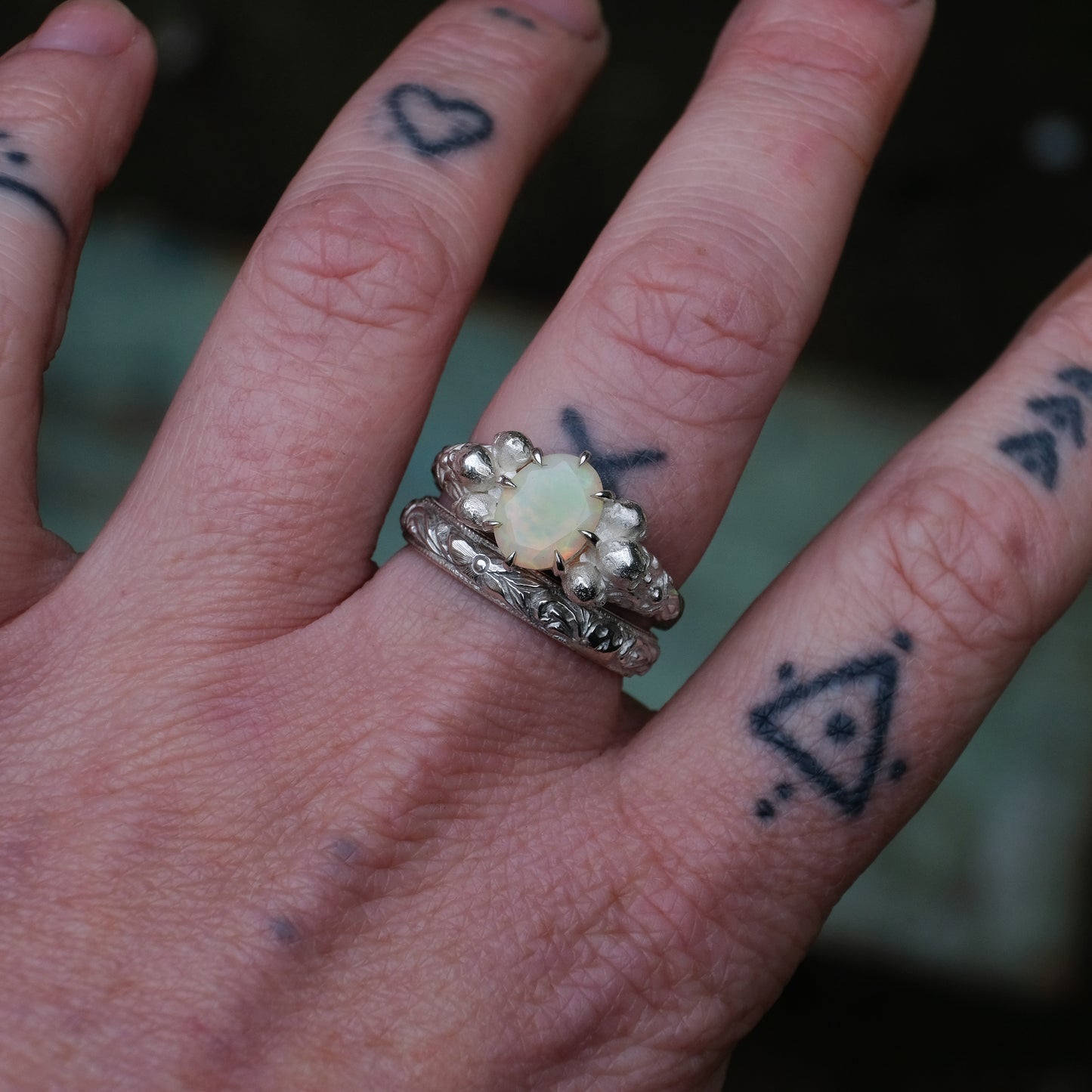 Silver band engraved with skulls, flourishes and flowers by Charlie Shires with cerberus skull and opal ring