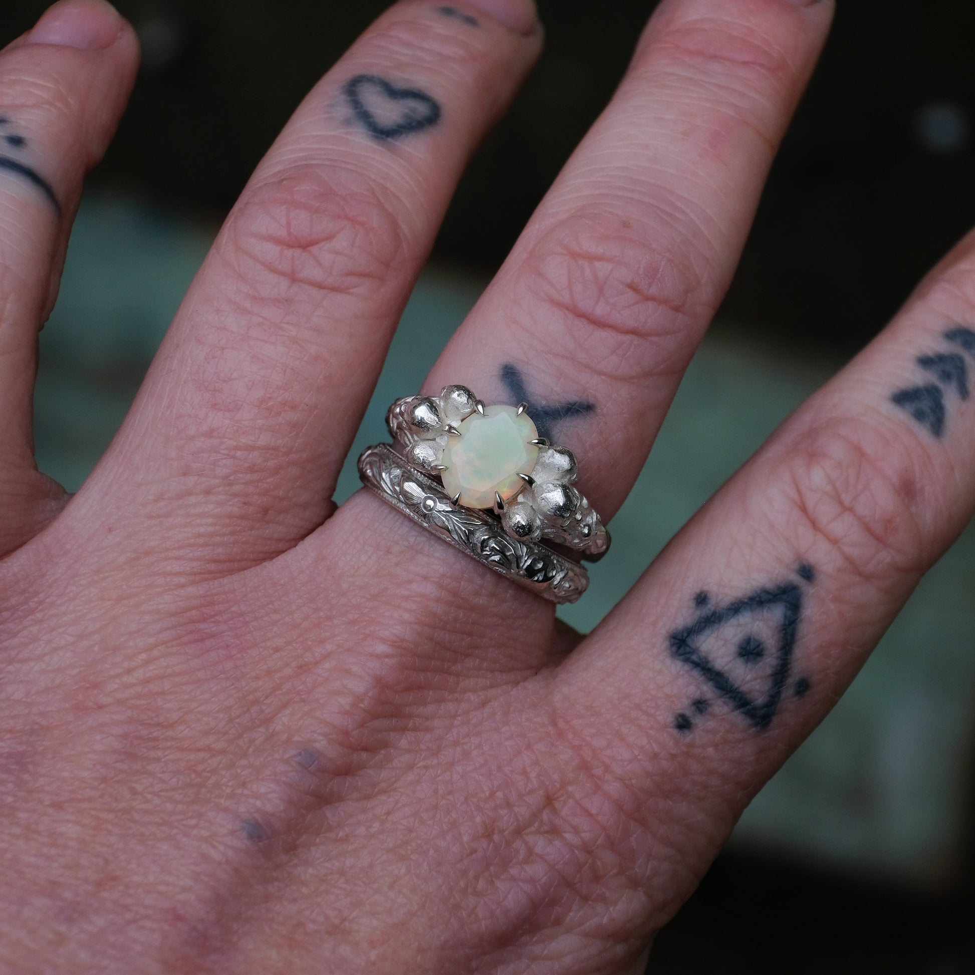 Silver band engraved with skulls, flourishes and flowers by Charlie Shires with cerberus skull and opal ring