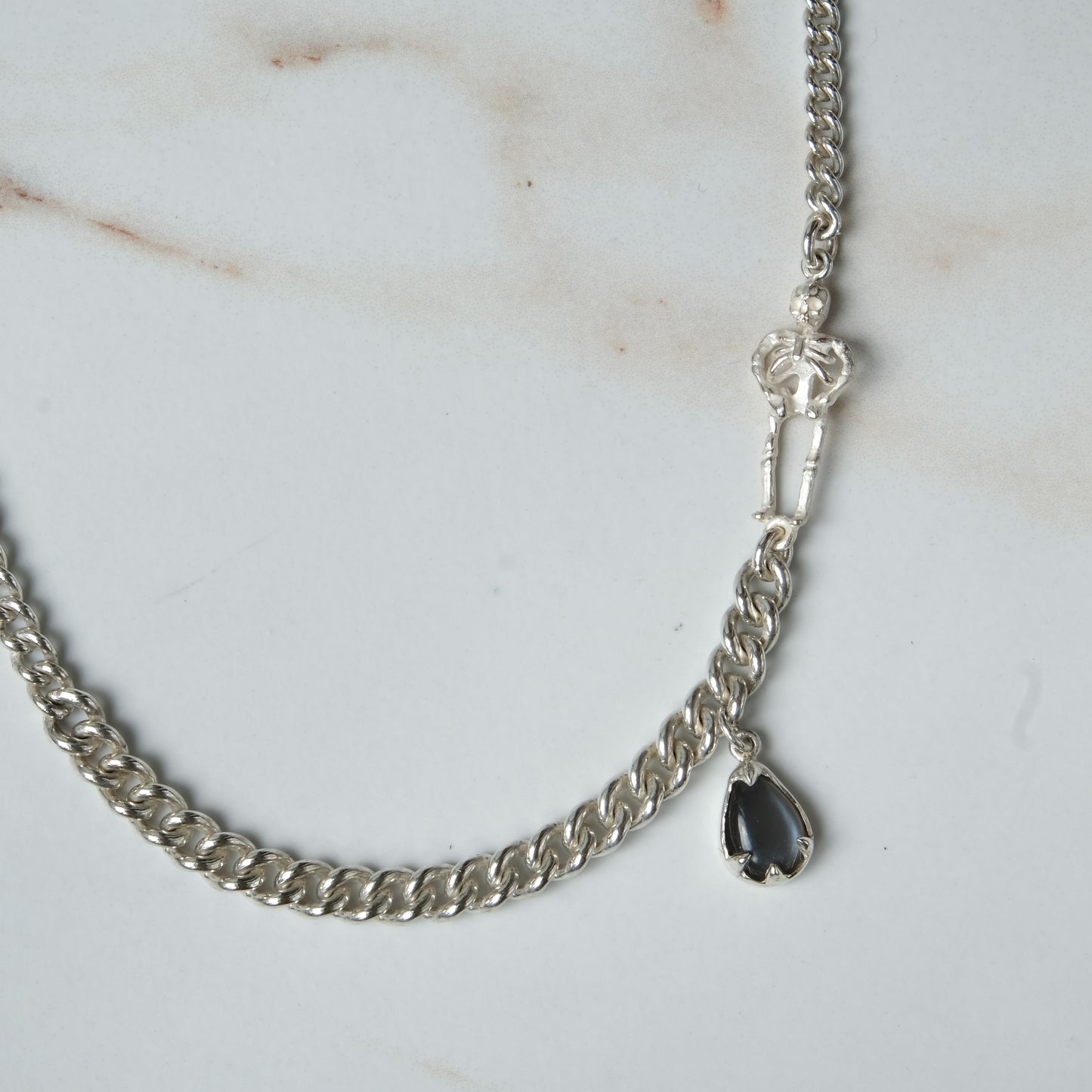 Sterling silver curb link necklace with skeleton and hanging moonstone. Photographed on white background. Made in London by Charlie Shires