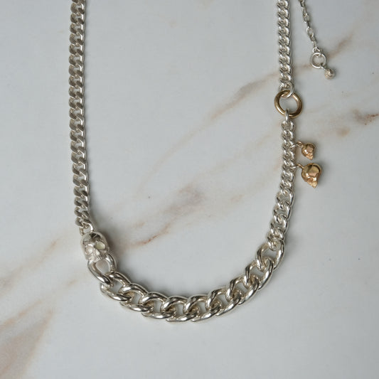 Heavy weight sterling silver curb link chain descending in size. 9ct yellow gold skulls hang off center from links. Handmade in London by Charlie Shires