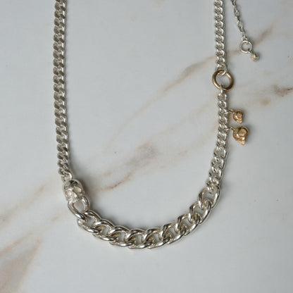 Heavy weight sterling silver curb link chain descending in size. 9ct yellow gold skulls hang off center from links. Handmade in London by Charlie Shires