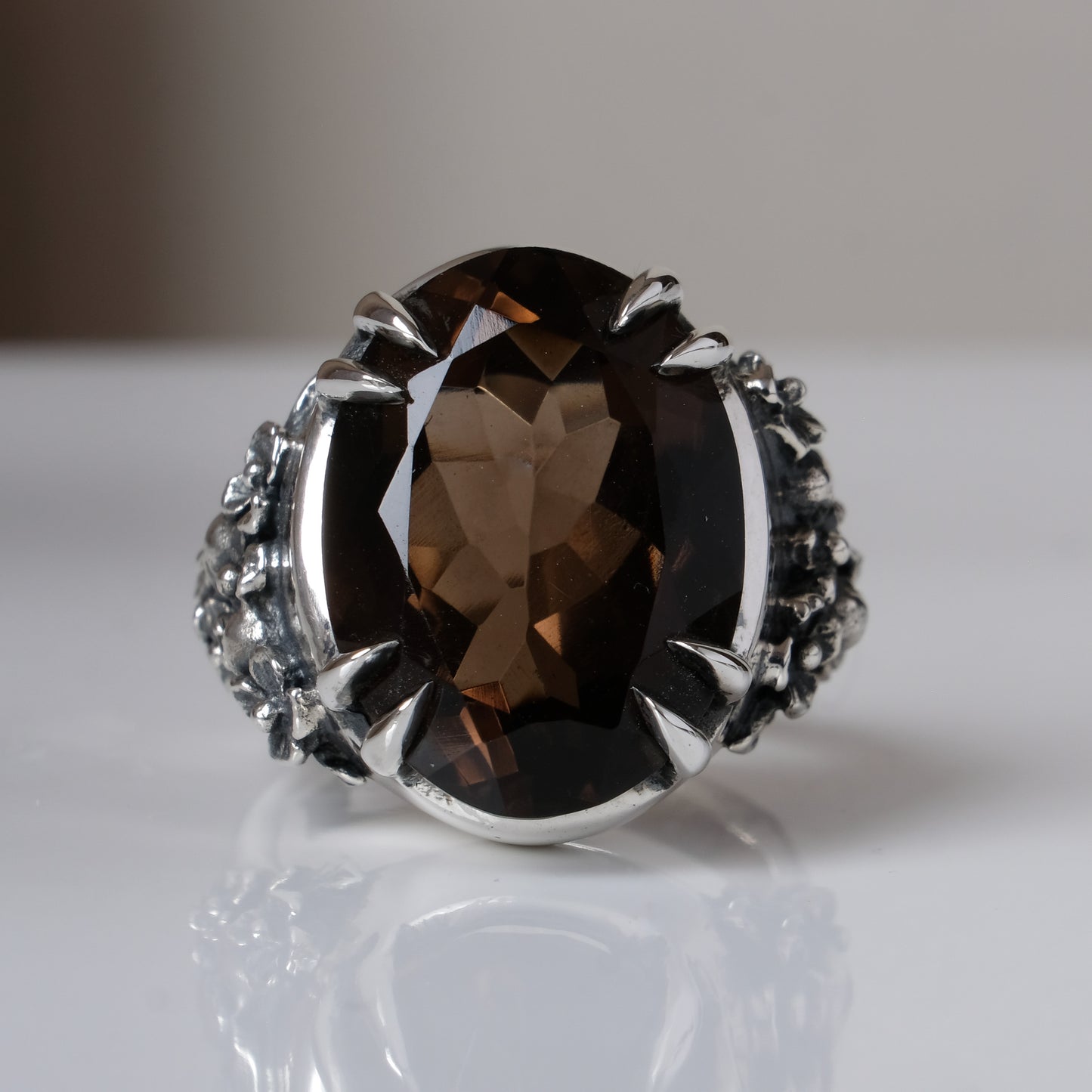Sterling silver ring with a large smokey quartz gemstone on a reflective surface