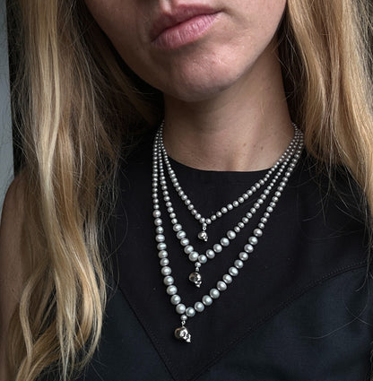 Hand strung grey freshwater pearls with a small, medium and large sterling silver skull, made by hand in London by Charlie Shires