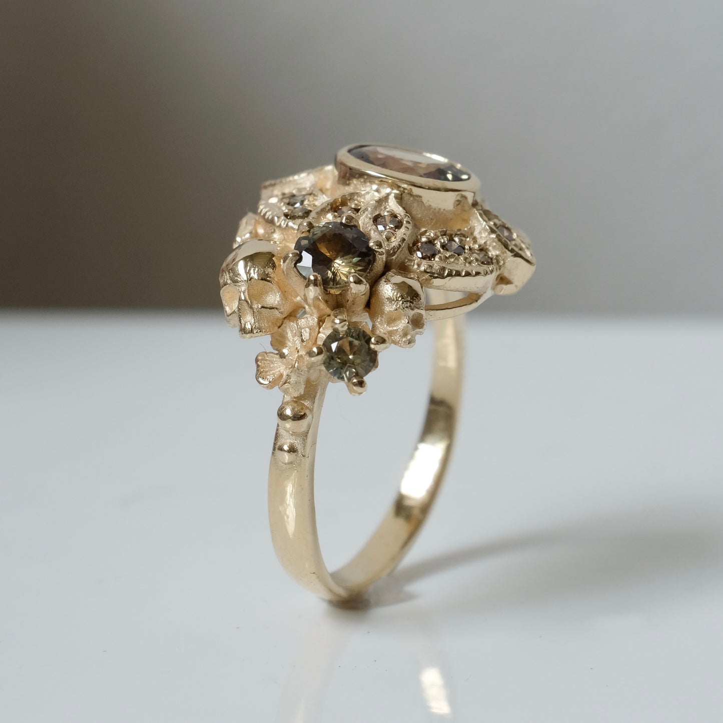 The Helen engagement ring with colour change sapphire, champagne diamond with skulls and flowers made in 9ct yellow gold in London by Charlie Shires