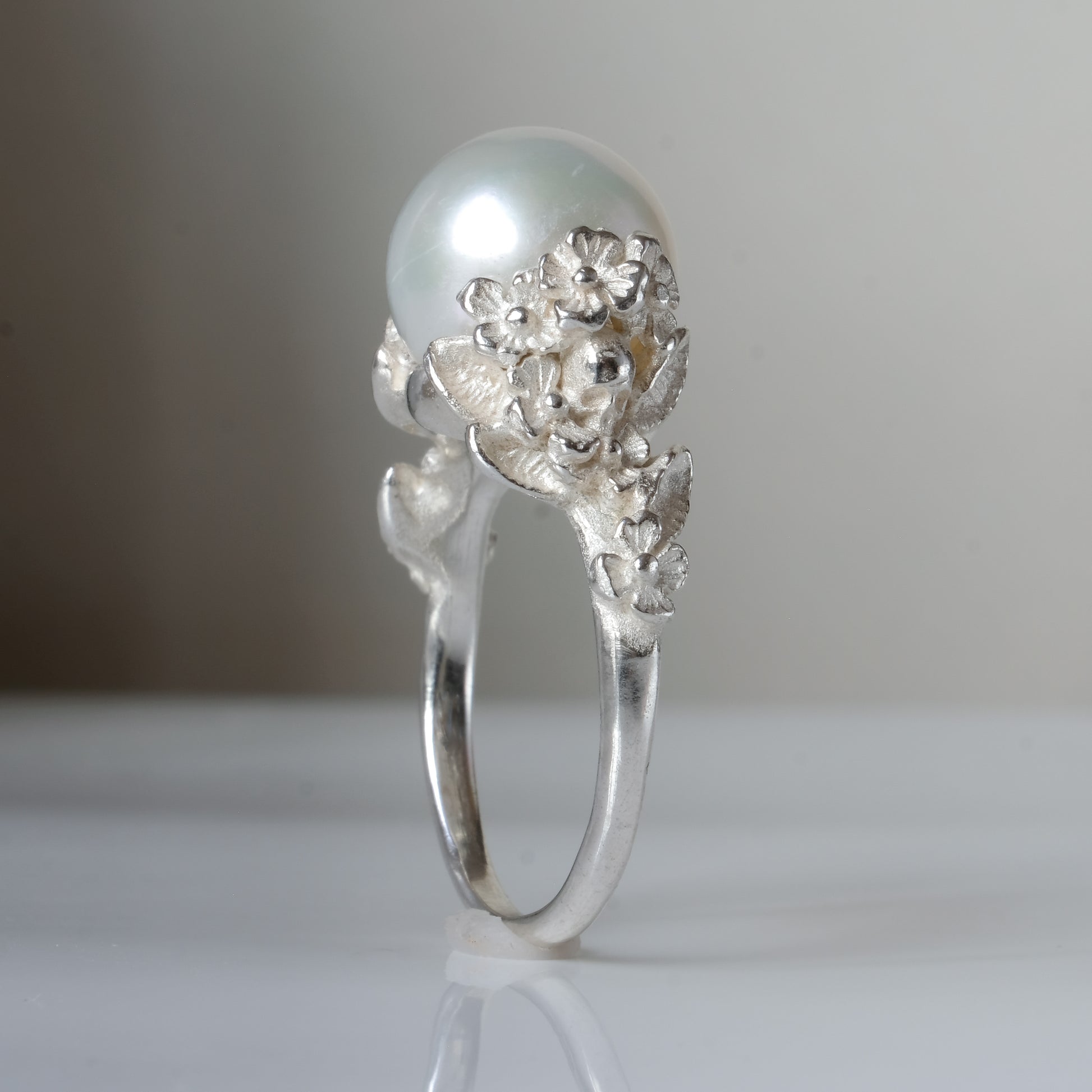 Large pearl ring with flower and skull motif down band. made in sterling silver in London by Charlie Shires