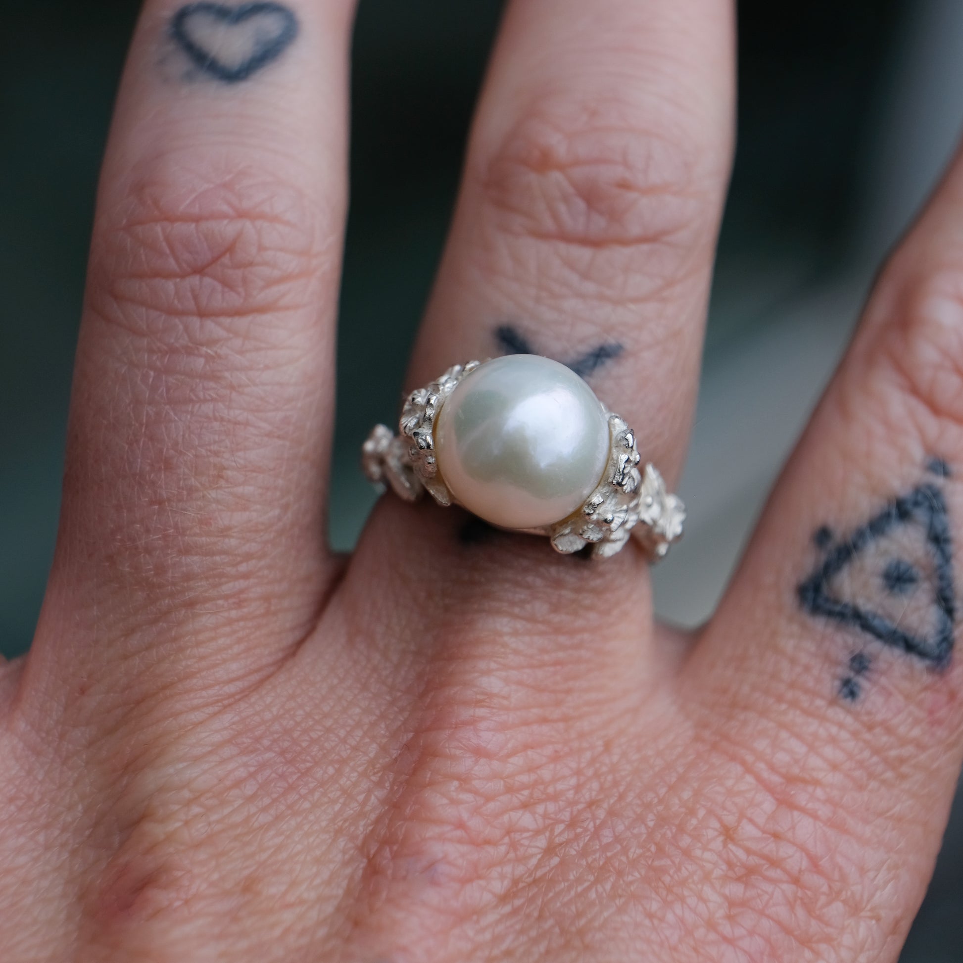 Large pearl ring with flower and skull motif down band. made in sterling silver in London by Charlie Shires