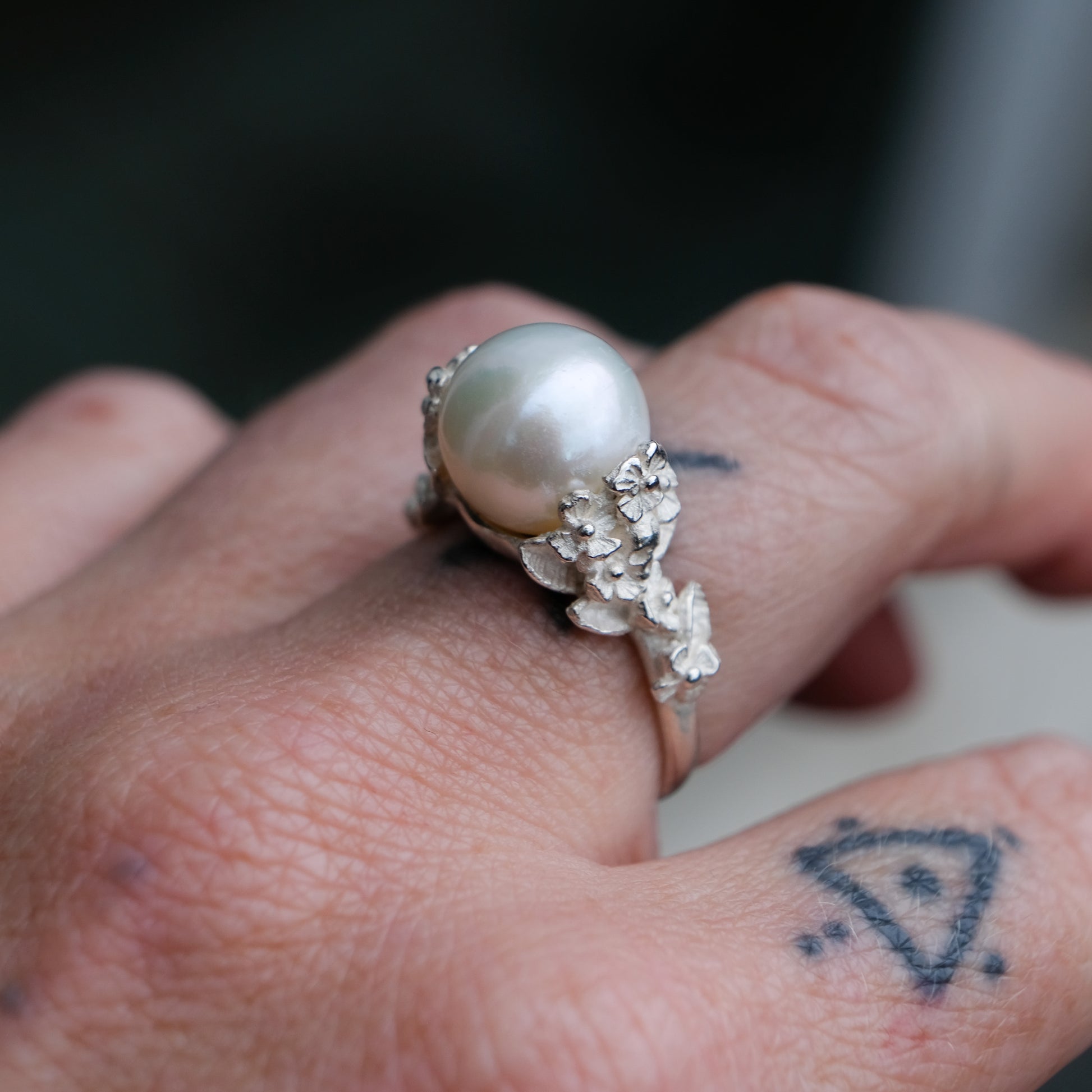 Large pearl ring with flower and skull motif down band. made in sterling silver in London by Charlie Shires