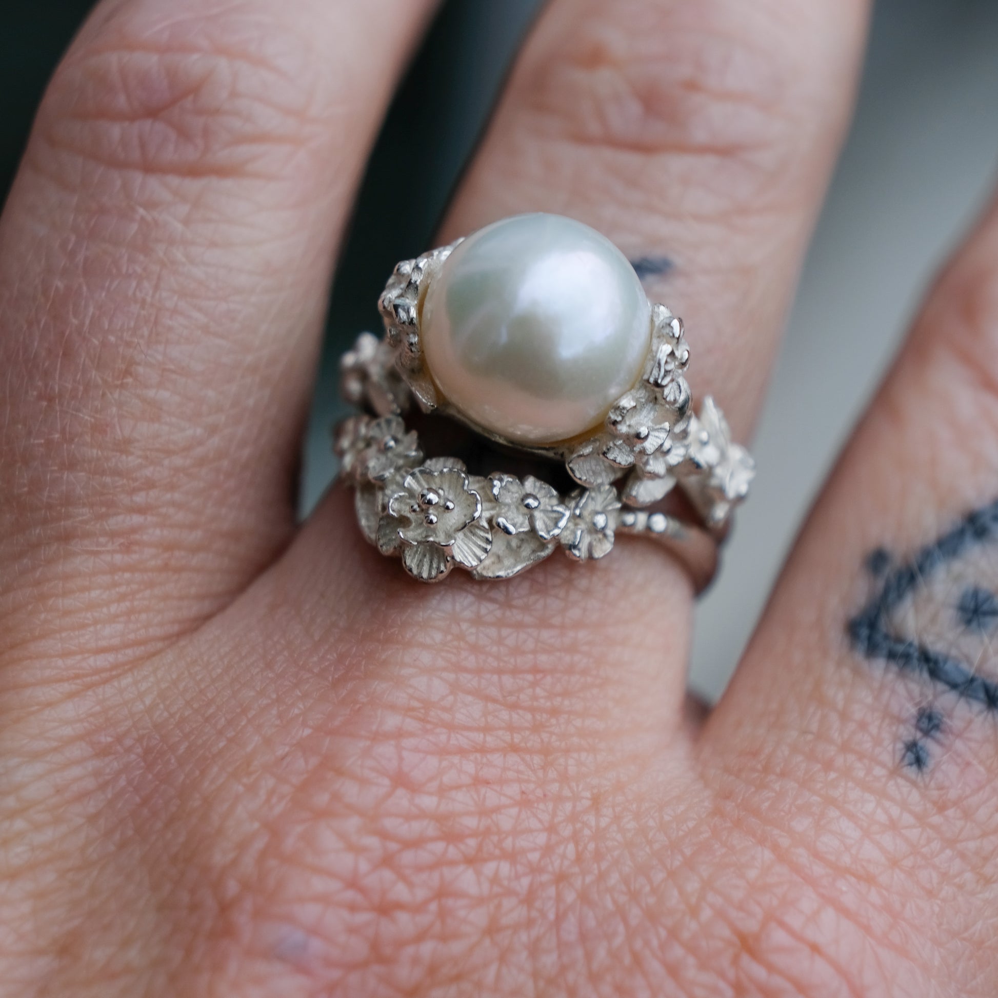 Large pearl ring with flower and skull motif down band. made in sterling silver in London by Charlie Shires