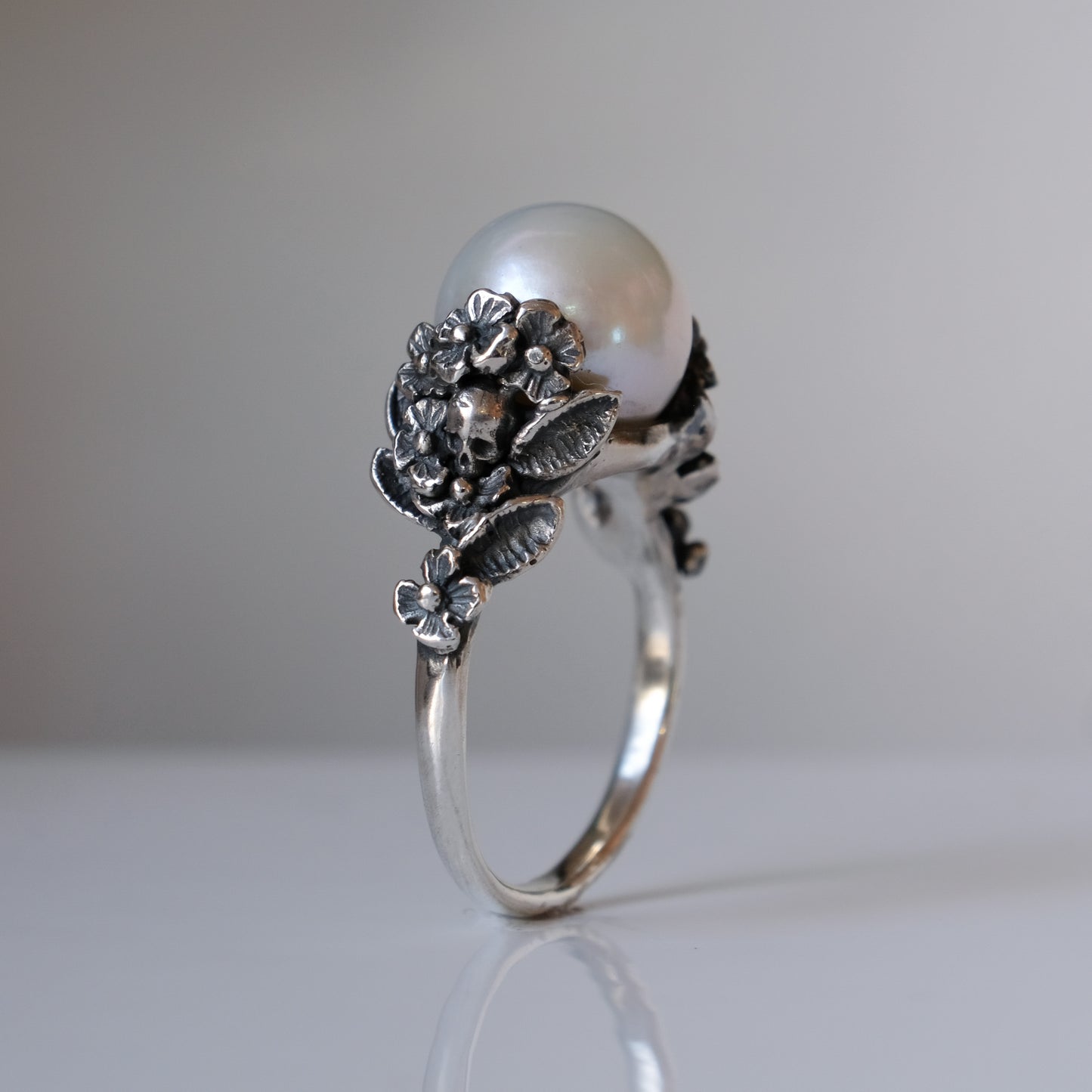 Large pearl ring with flower and skull motif down band. made in sterling silver in London by Charlie Shires