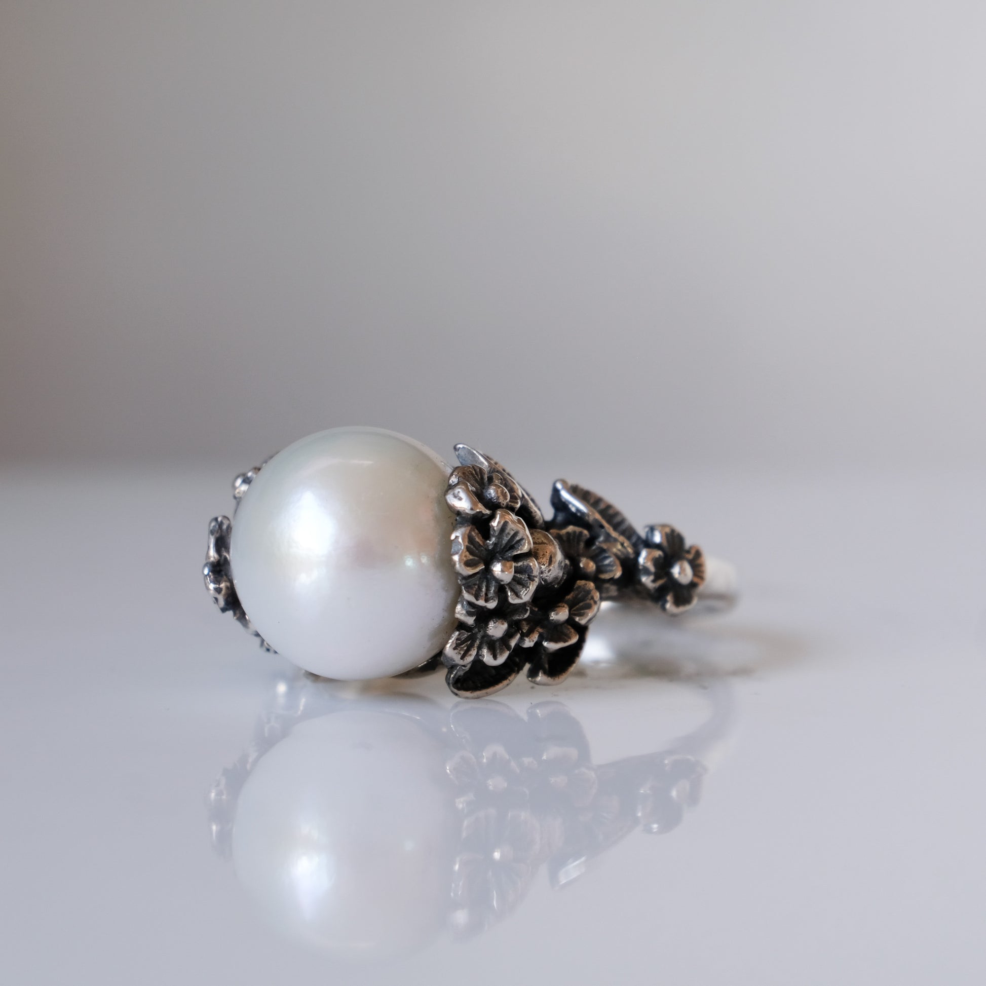 Large pearl ring with flower and skull motif down band. made in sterling silver in London by Charlie Shires