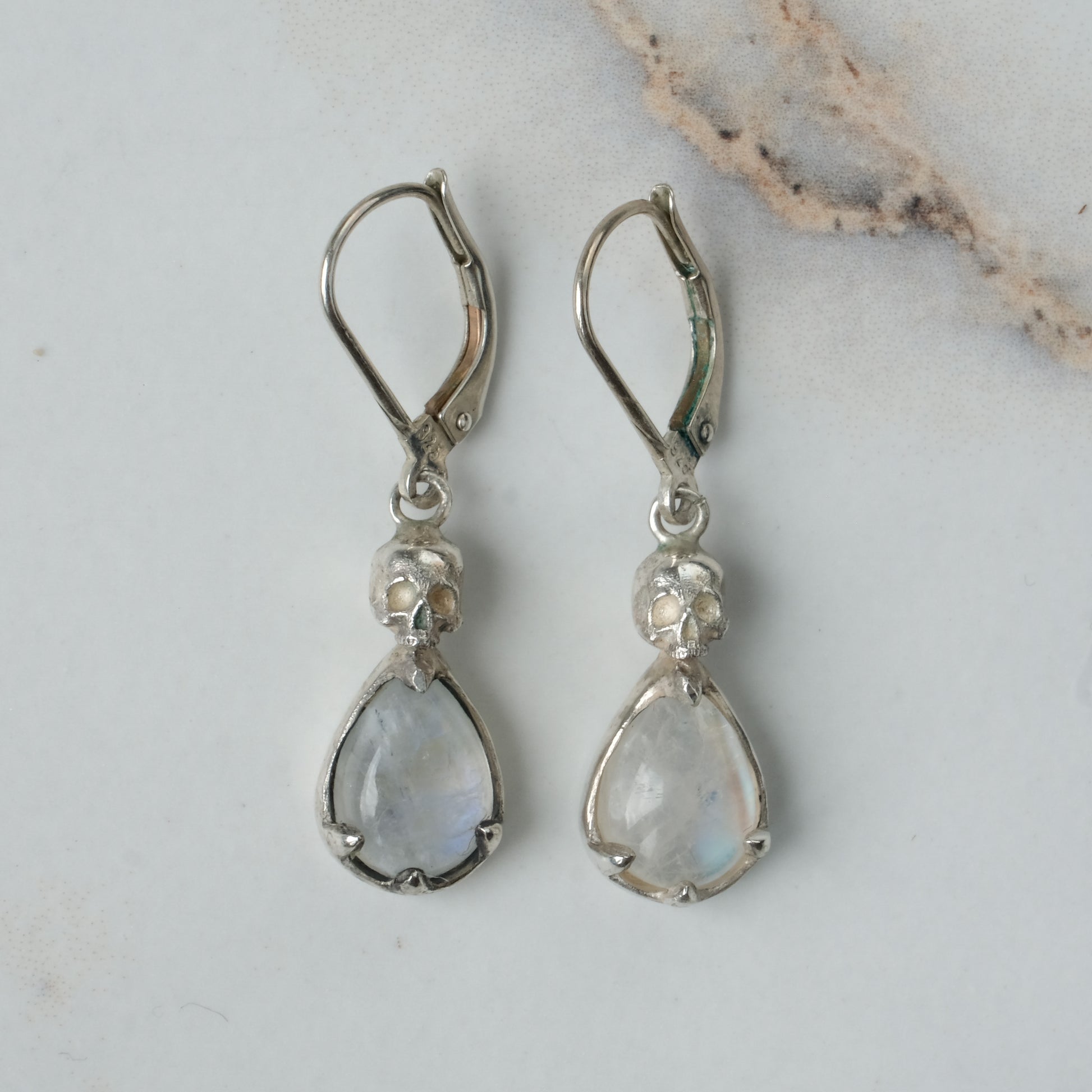 Skull earrings with claw set pear shaped moonstones made in sterling silver by Charlie Shires