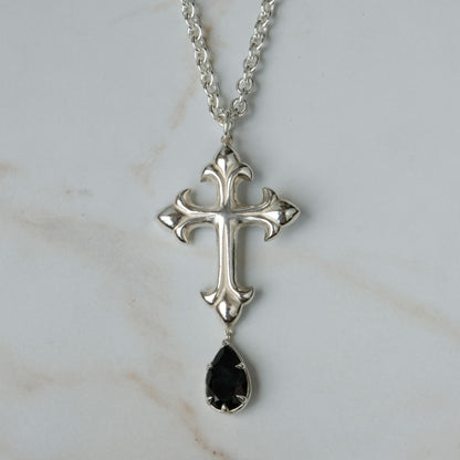 Hand carved crucifix necklace with pear shaped claw set drop black spinel. Made in sterling silver by Charlie Shires in London