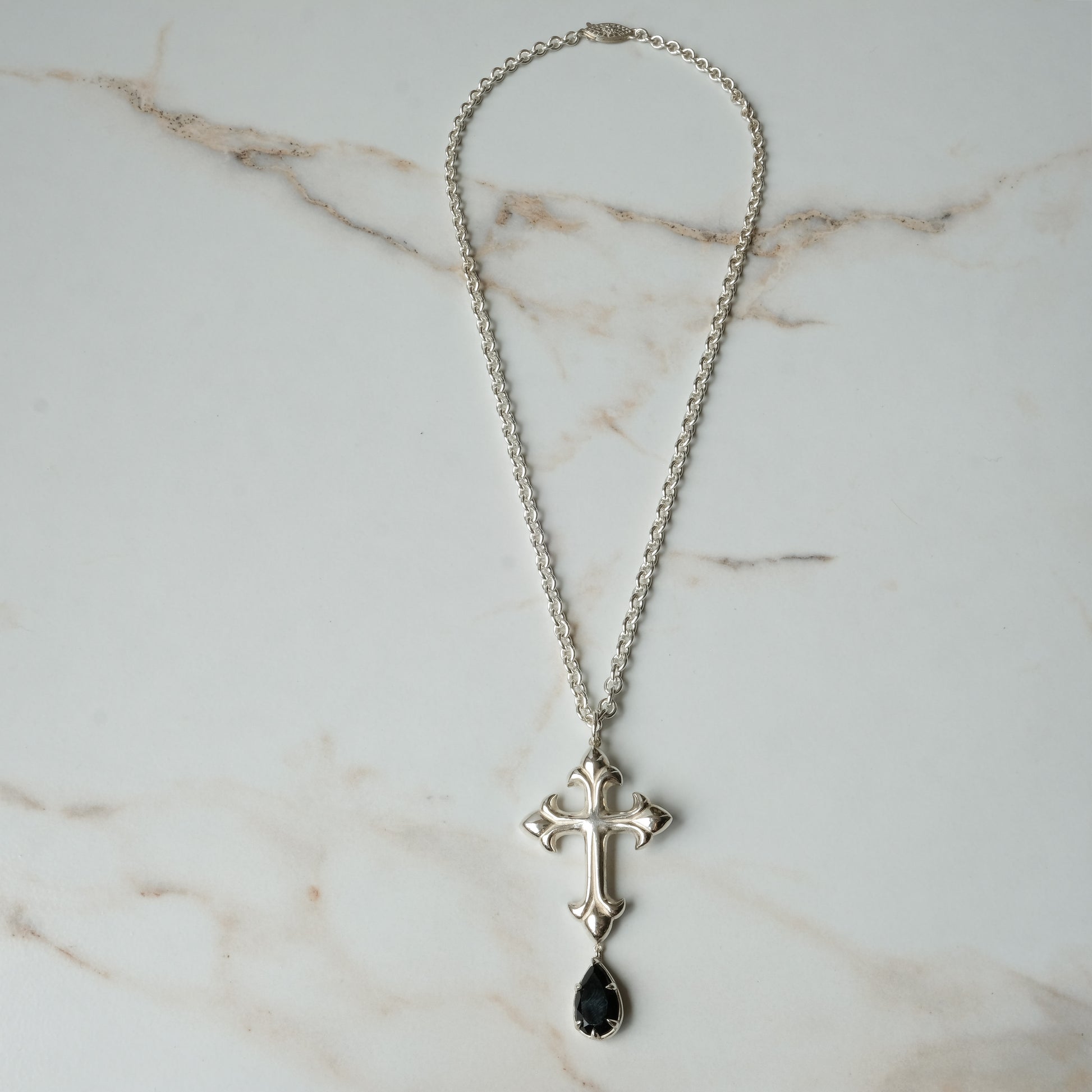 Hand carved crucifix necklace with pear shaped claw set drop black spinel. Made in sterling silver by Charlie Shires in London