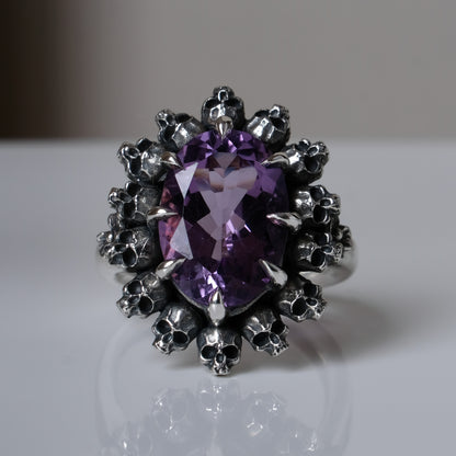 Ring with claw set amethyst and silver skull design on a white background