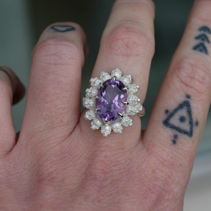 Ring with claw set amethyst gemstone and silver skull design worn on hand with tattoos
