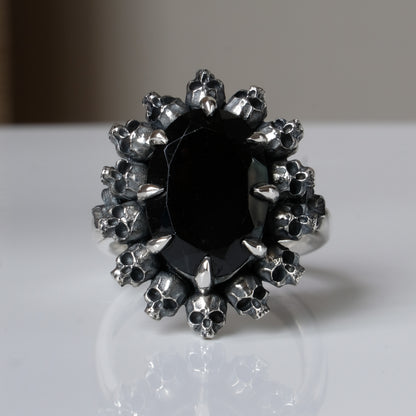 Ring with claw set black spinel gemstone and silver skull design on a white background