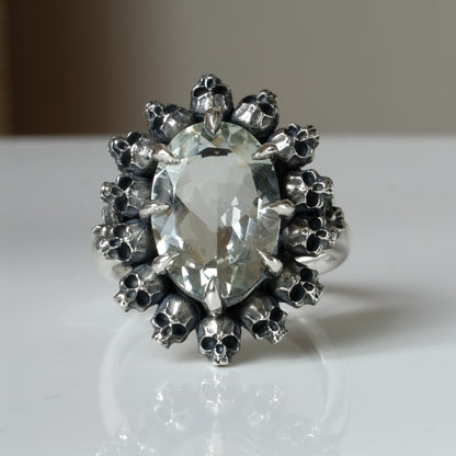 Ring with claw set with mint quartz gemstone and silver skull design on a white background