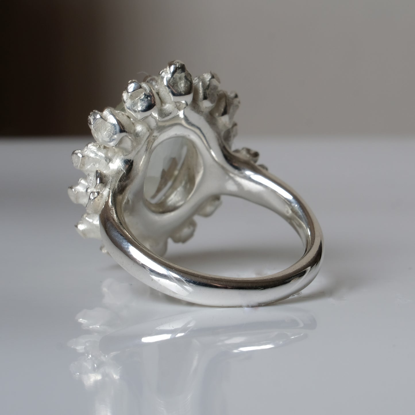 Ring with claw set mint quartz gemstone and silver skull design on a white background
