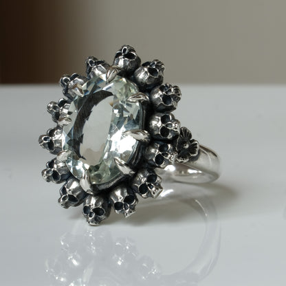 Ring with claw set with mint quartz gemstone and silver skull design on a white background