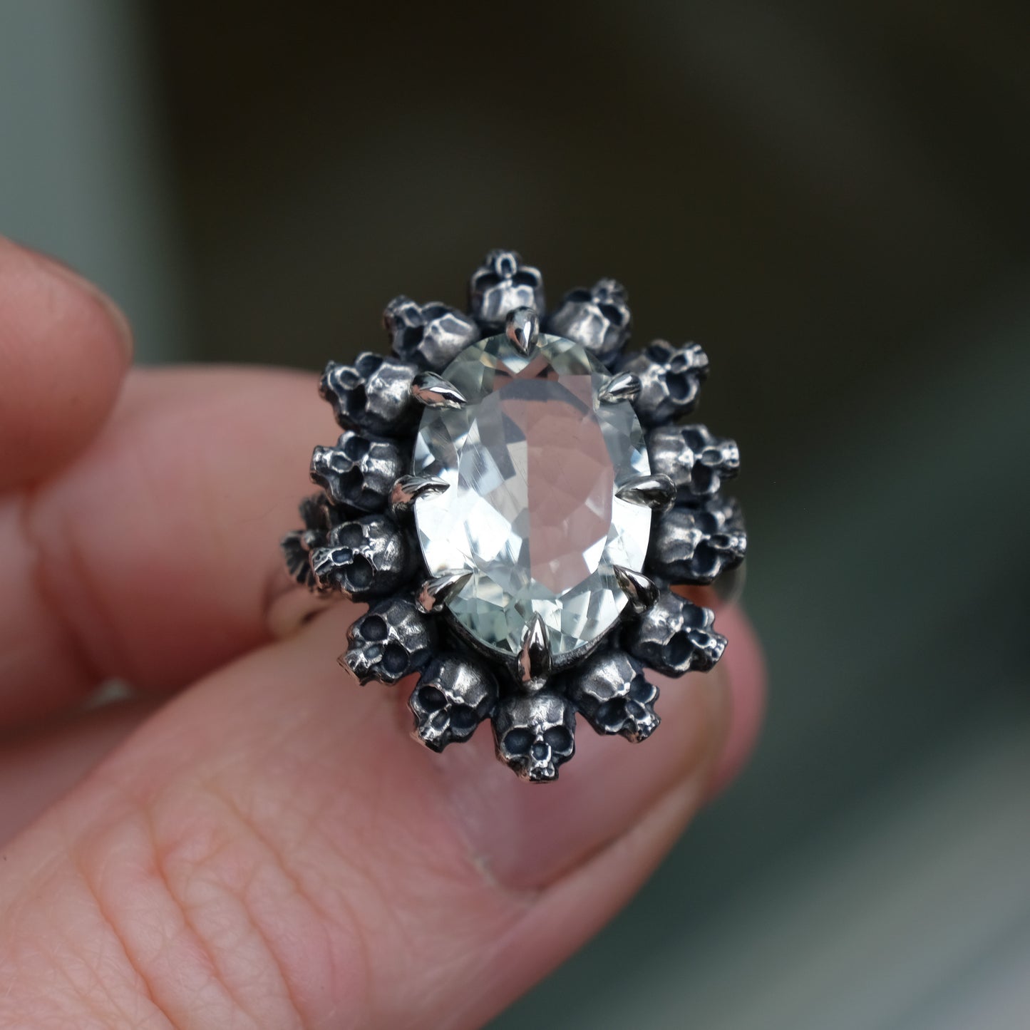 Ring with claw set with mint quartz gemstone and silver skull design  with green background