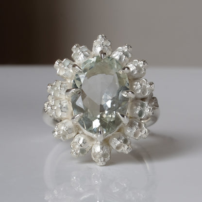Ring with claw set with mint quartz gemstone and silver skull design on a white background