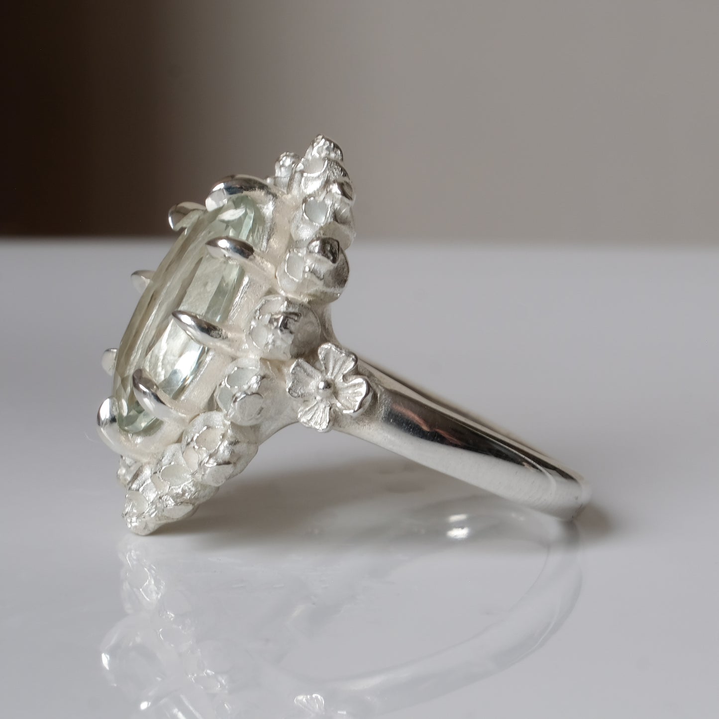 Ring with claw set mint quartz gemstone and silver skull design on a white background