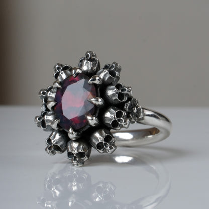 Silver ring with black opal gemstone in skull halo design on reflective background handmade in London, UK