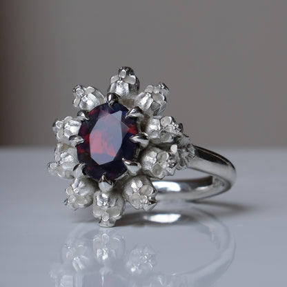 Silver ring with black opal gemstone in skull halo design on reflective background handmade in London, UK