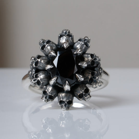 Silver ring with black spinel gemstone in skull halo design on reflective background handmade in London, UK