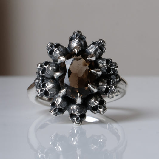 Silver ring with brown smokey quartz gemstone in skull halo design on reflective background handmade in London, UK