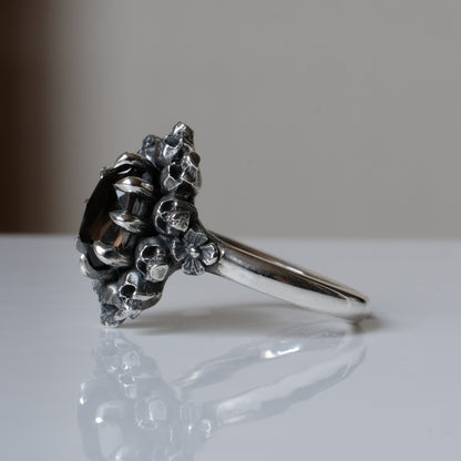 Silver ring with brown smokey quartz gemstone in skull halo design on reflective background handmade in London, UK