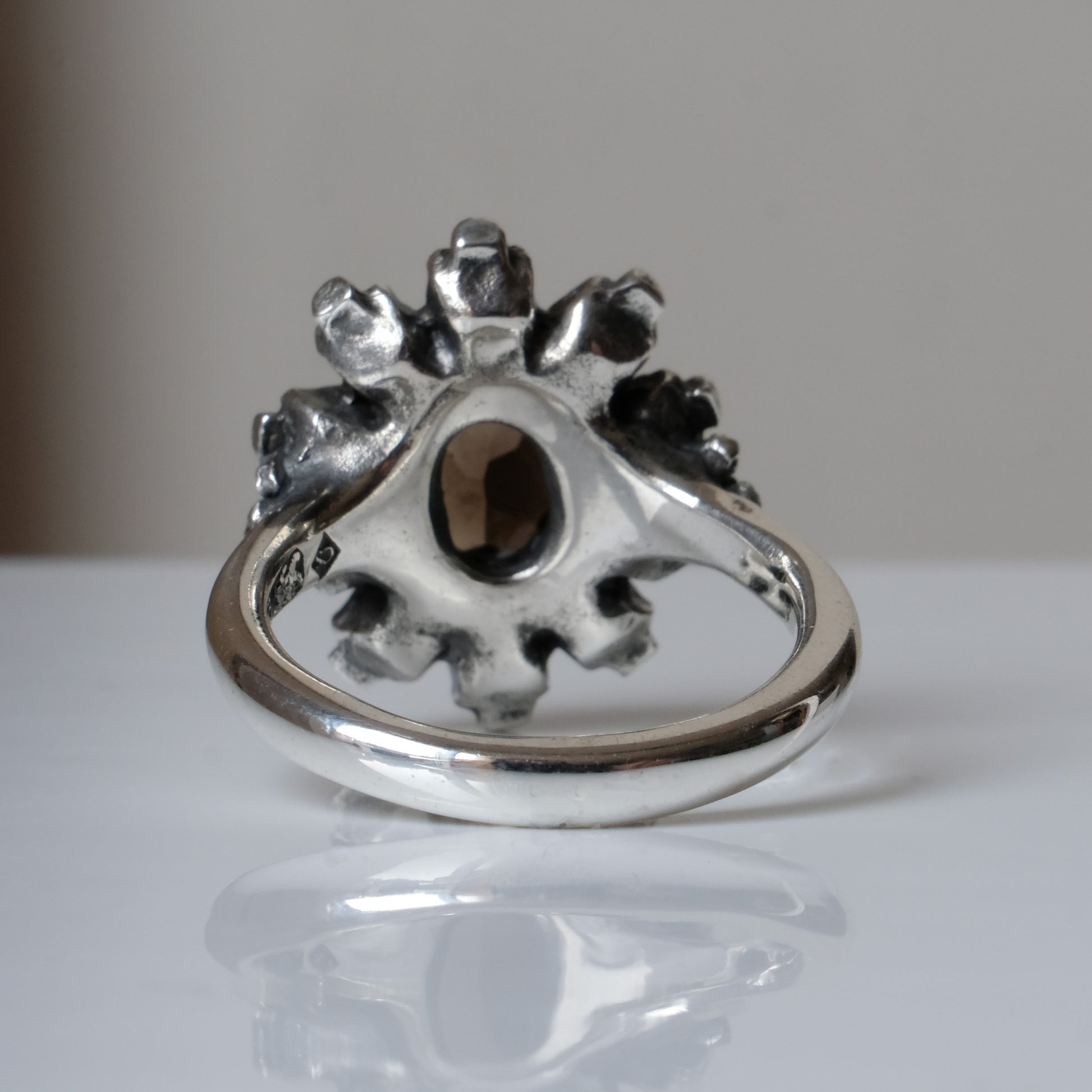 Silver ring with brown smokey quartz gemstone in skull halo design on reflective background handmade in London, UK