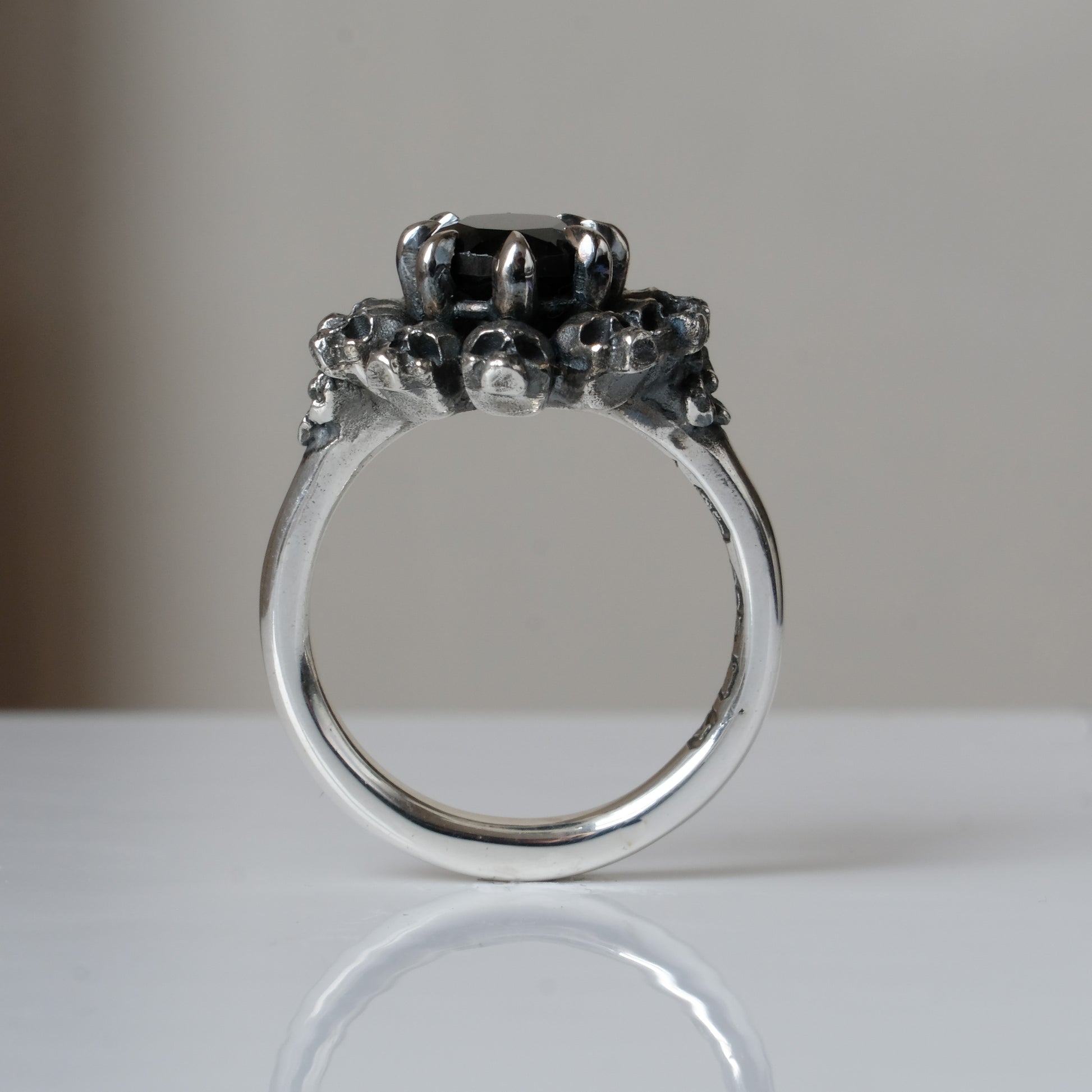 Silver ring with brown smokey quartz gemstone in skull halo design on reflective background handmade in London, UK