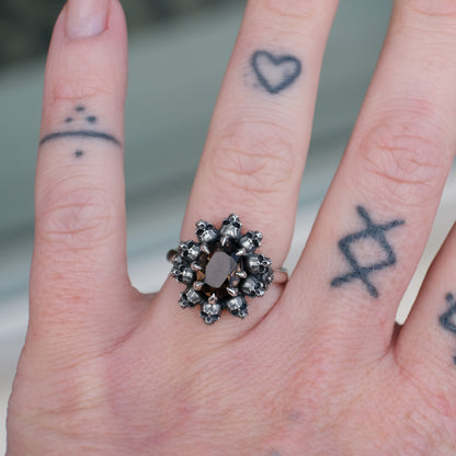 Silver ring with brown smokey quartz gemstone in skull halo design worn on hand with tattoos handmade in London, UK