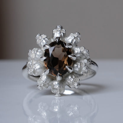 Silver ring with brown smokey quartz gemstone in skull halo design on reflective background handmade in London, UK