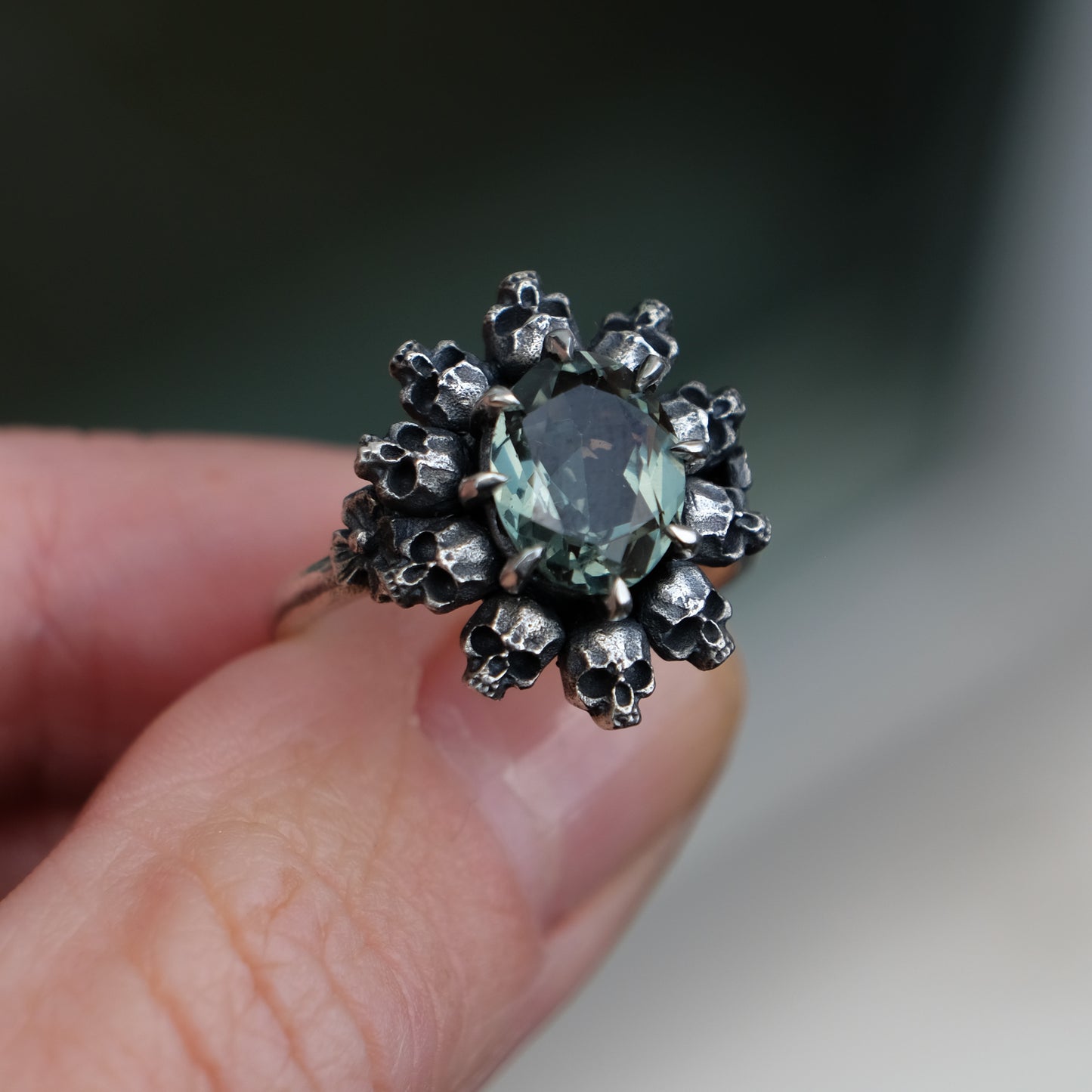 Skull halo ring with synthetic tourmaline stone and flowers on side of band by Charlie Shires