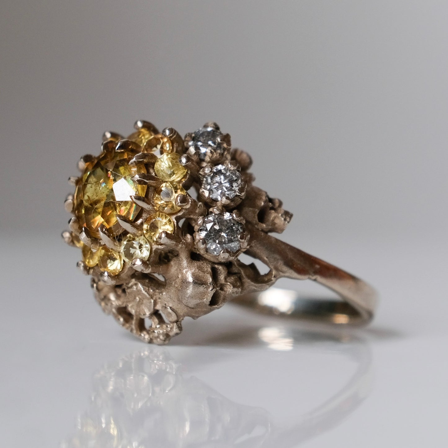 Salacia engagement ring with central Sphene and sapphire halo, salt and pepper diamonds, skulls and flowers. Made in 14t white gold in London by Charlie Shires