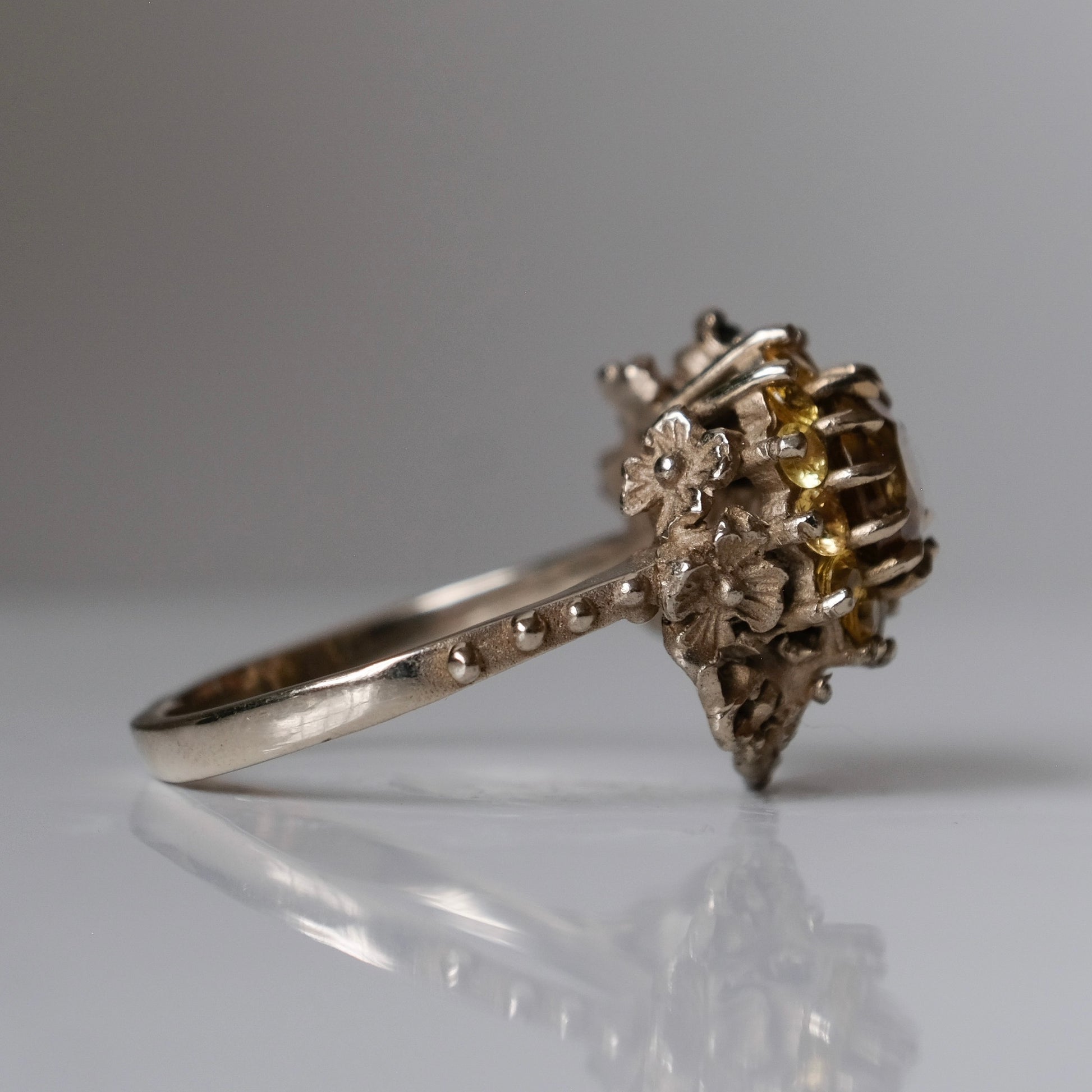 Salacia engagement ring with central Sphene and sapphire halo, salt and pepper diamonds, skulls and flowers. Made in 14ct white gold in London by Charlie Shires