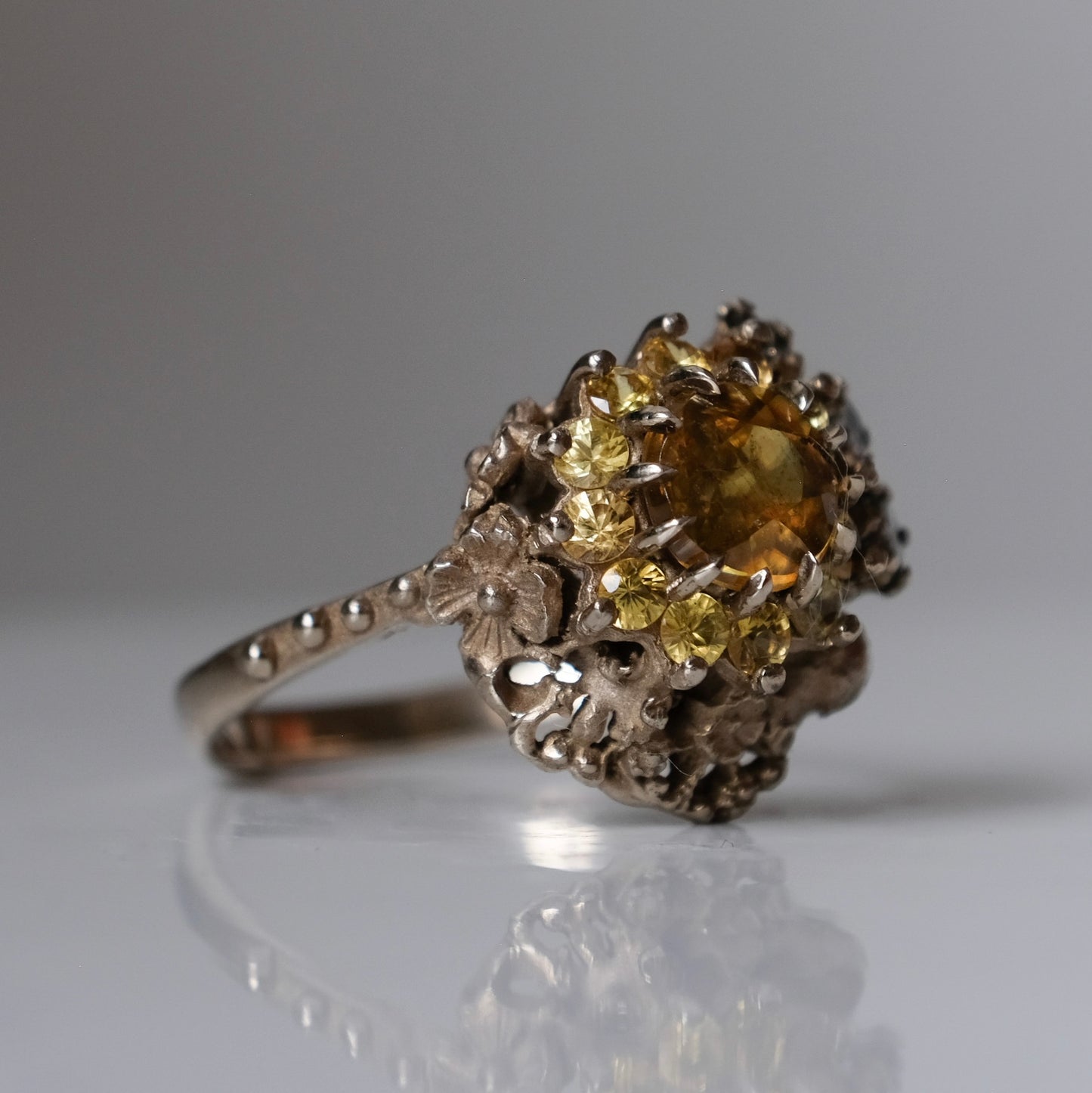 Salacia engagement ring with central Sphene and sapphire halo, salt and pepper diamonds, skulls and flowers. Made in 14ct white gold in London by Charlie Shires