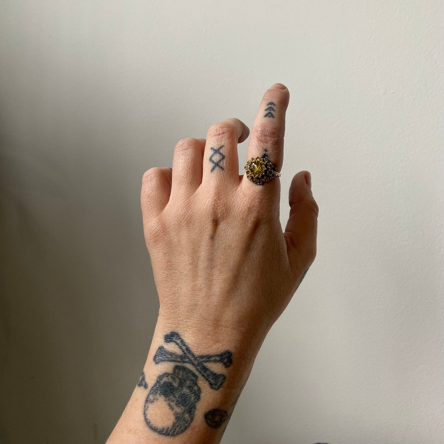 Salacia engagement ring with central Sphene and sapphire halo, salt and pepper diamonds, skulls and flowers. Made in 14ct white gold in London by Charlie Shires