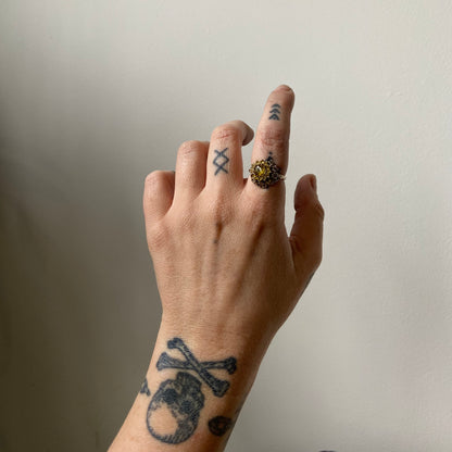 Salacia engagement ring with central Sphene and sapphire halo, salt and pepper diamonds, skulls and flowers. Made in 14ct white gold in London by Charlie Shires