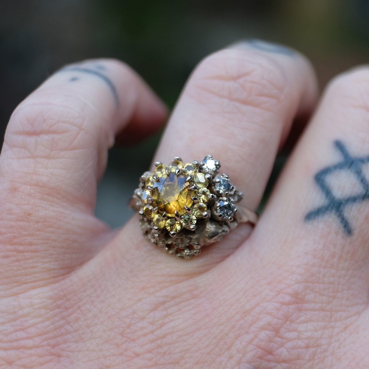 Salacia engagement ring with central Sphene and sapphire halo, salt and pepper diamonds, skulls and flowers. Made in 14ct white gold in London by Charlie Shires