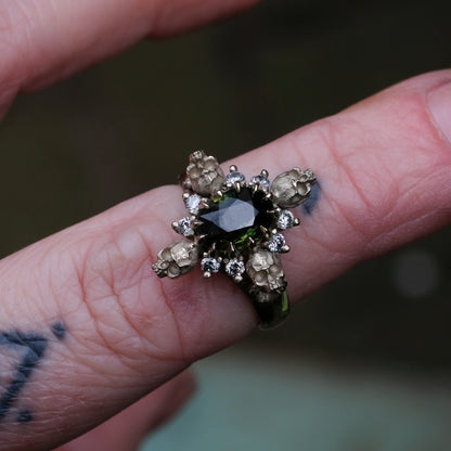 14ct white gold parti sapphire ring with halo of diamonds and skulls. Flowers flank the side of the band. Handmade in London by Charlie Shires