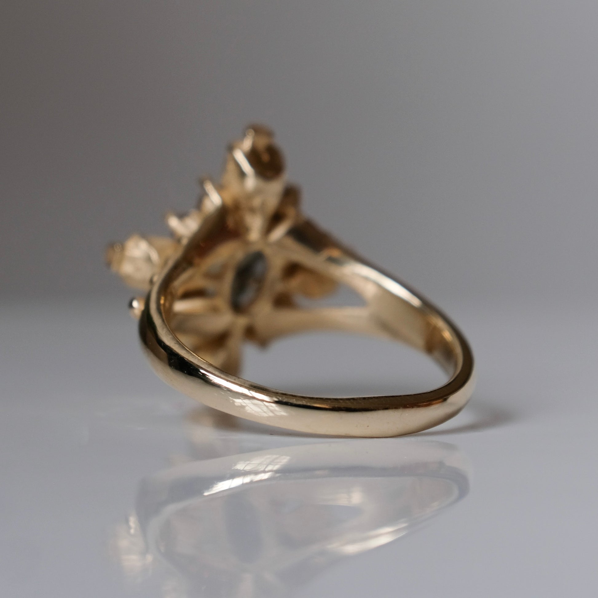 9ct yellow gold engagement ring with unheated sapphire and champagne diamond halo decorated with 4 skulls. 
Handmade in London by Charlie Shires