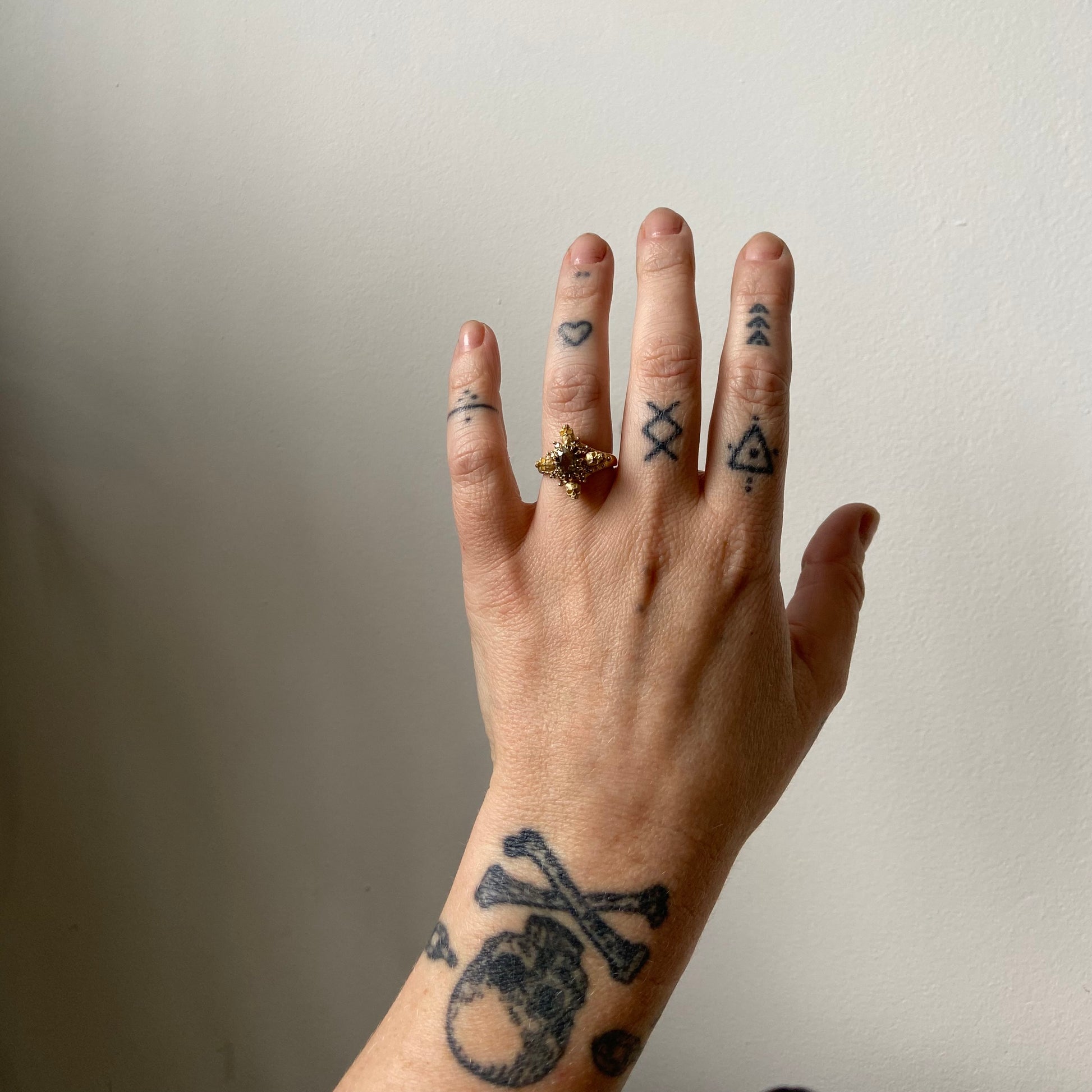 9ct yellow gold engagement ring with unheated sapphire and champagne diamond halo decorated with 4 skulls. 
Handmade in London by Charlie Shires