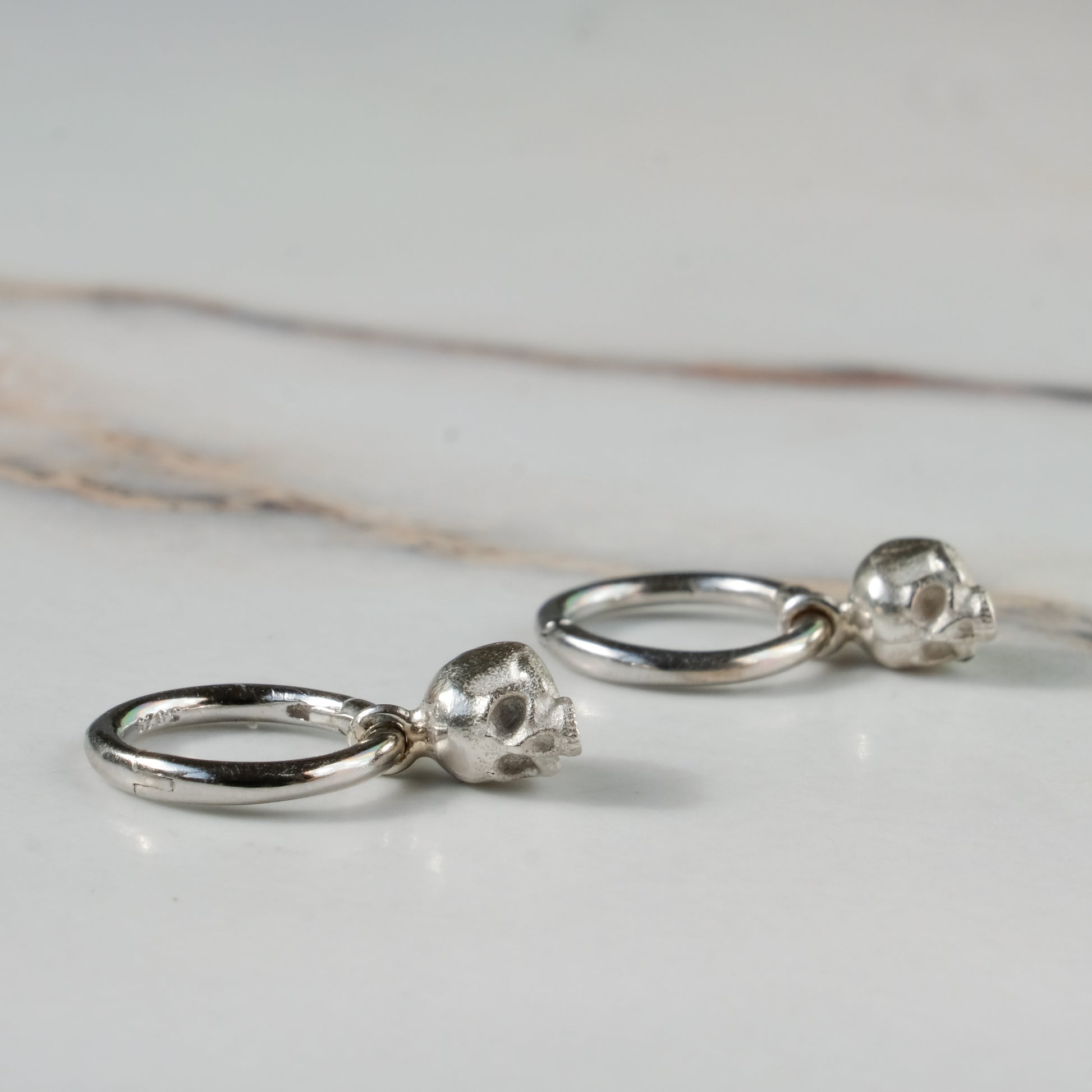Sterling silver skull huggie hoop earrings made in London by Charlie Shires