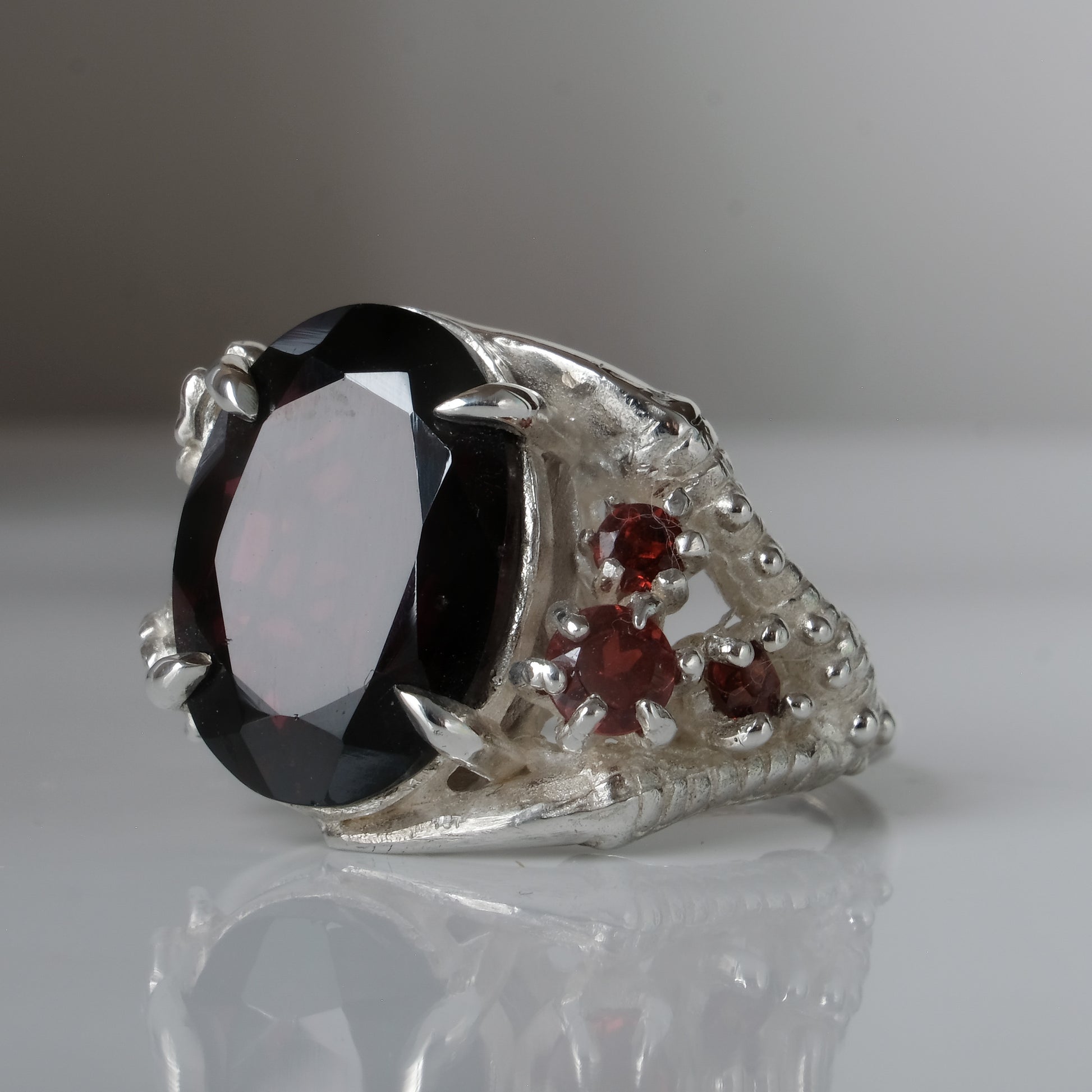 Silver birds talon claw ring with garnet stones by Charlie Shires