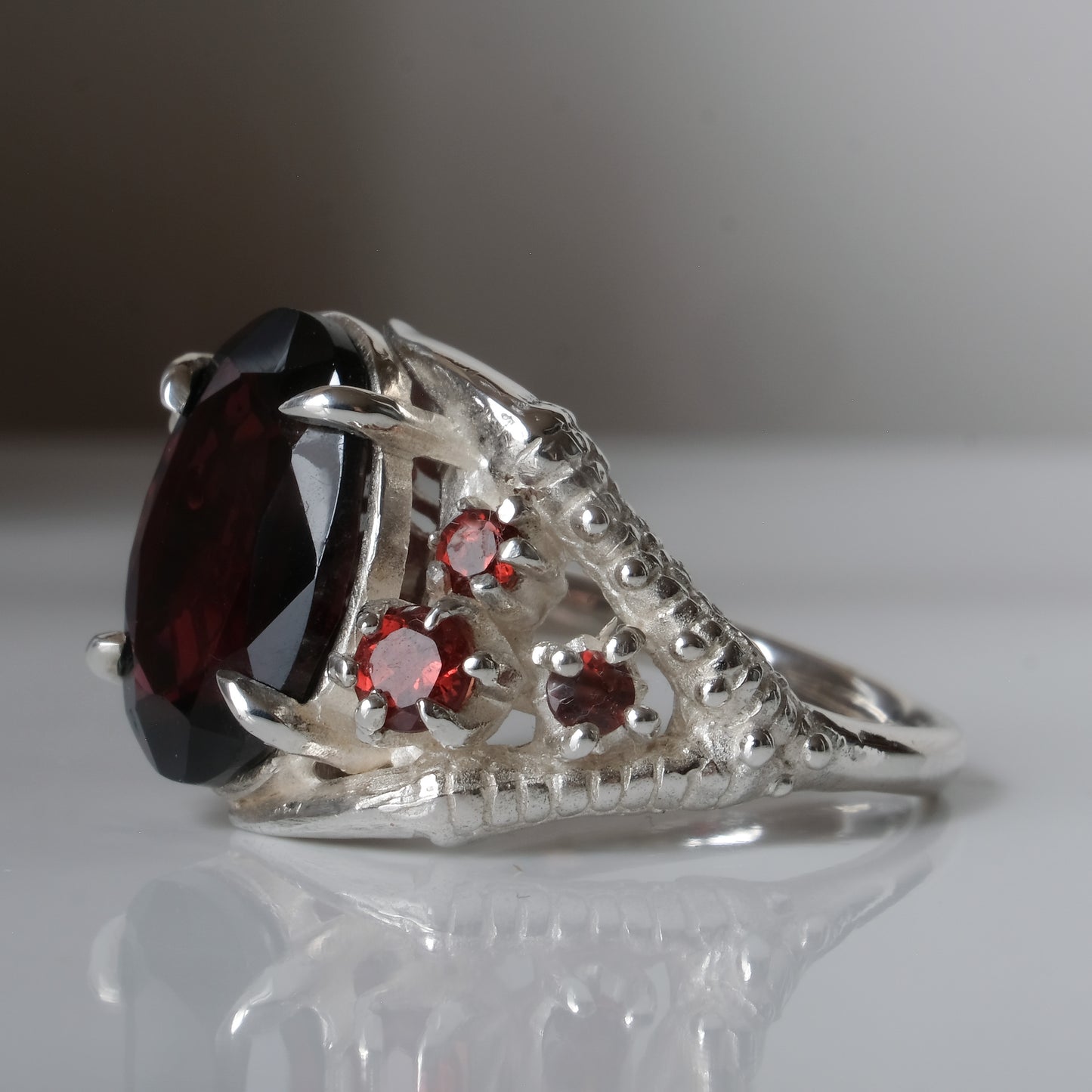 Silver birds talon claw ring with garnet stones by Charlie Shires