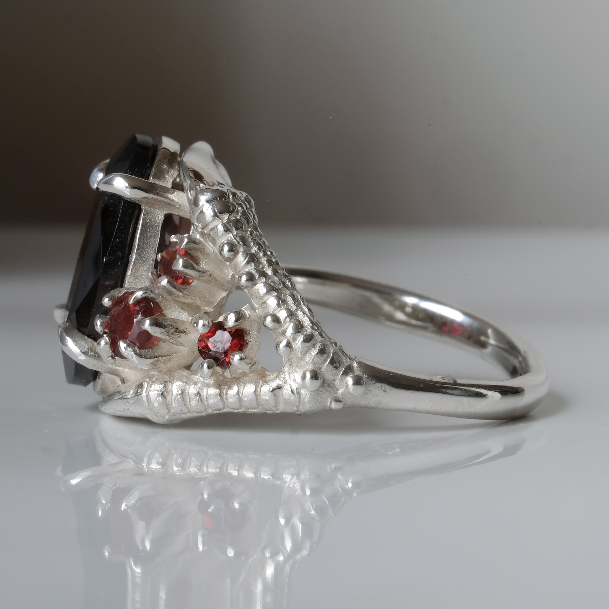 Silver birds talon claw ring with garnet stones by Charlie Shires